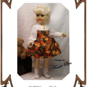 May include: A doll dress pattern for a 14.5 inch Toni doll. The pattern is for a white blouse with a lace trim and a brown, green, and orange skirt with a fall leaf print. The pattern is titled "A Day at Home" and is designed by Marsha Olson.