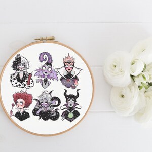 May include: Embroidered hoop art featuring Disney villains. The villains include Cruella de Vil, Maleficent, Ursula, the Evil Queen, and Queen of Hearts. The hoop is white with a black background and the villains are all in black and white.