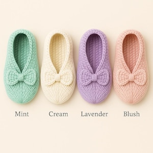 May include: Four knitted slippers in mint, cream, lavender, and blush colours. Each slipper features a bow detail on the front. The slippers are arranged in a row, with the colour names printed below each one.