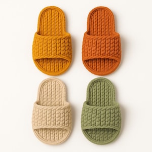 May include: Four pairs of open-toe slippers in a variety of colors: mustard yellow, burnt orange, beige, and olive green. The slippers have a thick, textured knit design, perfect for indoor wear. The slippers are arranged in a square formation.