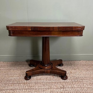 Può includere: Un tavolo antico marrone scuro con piano rettangolare e base a piedistallo. Il tavolo ha una finitura lucida ed è sostenuto da una colonna centrale e da una base a quattro gambe. Il tavolo è lungo circa 76 cm.