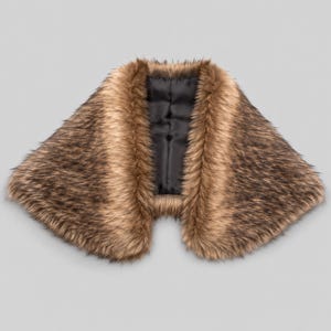 May include: A faux fur collar wrap featuring long, textured fibers in shades of brown and black. The accessory has a wide, curved shape that tapers toward the center, and it is lined with a smooth, solid black fabric on the inner side.
