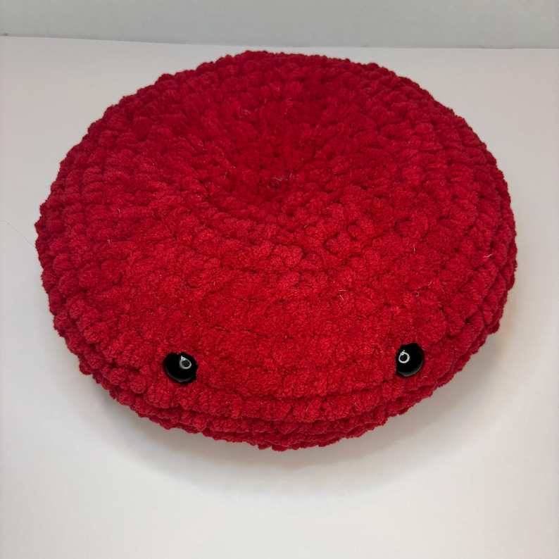 May include: A red plush toy shaped like a blood cell with black button eyes.