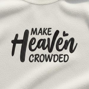 Puede incluir: Sudadera de color crema con la frase bordada "MAKE Heaven CROWDED" en escritura negra. El texto está centrado en el pecho, con un pequeño detalle de corazón encima de la "e" en "Heaven". La sudadera tiene cuello redondo.