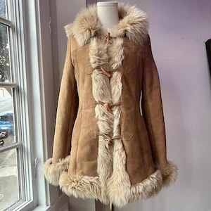 May include: A brown suede and shearling coat with a fur collar and toggle closures.