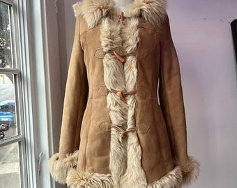 May include: A brown suede and shearling coat with a fur collar and toggle closures.