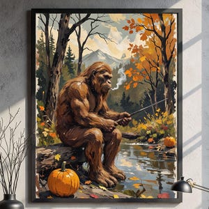 May include: A framed art print depicts a Sasquatch fishing in a stream. The artwork features a brown-furred creature sitting on a log, with autumn foliage and a pumpkin. The scene is set in a forest with a mountain backdrop.