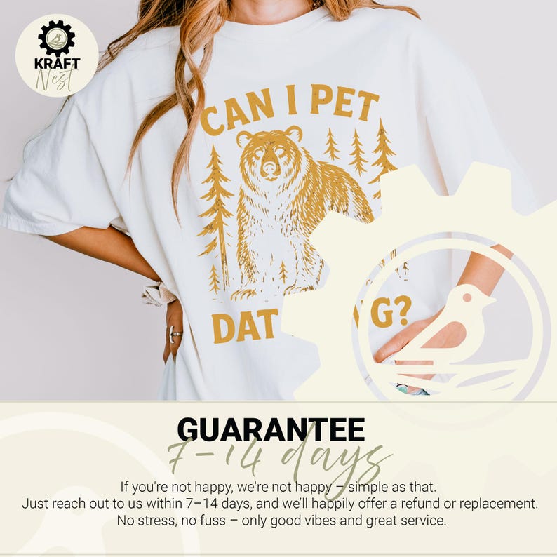 May include: Cream-colored t-shirt with a gold bear graphic and the text "CAN I PET DAT G?". The design includes trees, and the shirt has a relaxed fit. A guarantee is also printed on the bottom of the shirt.