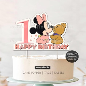 May include: Pink and white cake topper featuring a cartoon Minnie Mouse holding a teddy bear. The topper says "Happy Birthday" in pink and white letters.