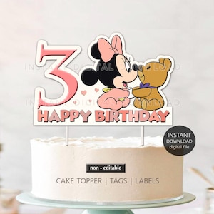 May include: Pink and white cake topper with a pink number 3, a cartoon image of a baby Minnie Mouse holding a teddy bear, and the words "Happy Birthday".