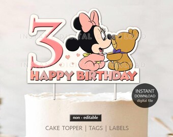 May include: Pink and white cake topper with a pink number 3, a cartoon image of a baby Minnie Mouse holding a teddy bear, and the words "Happy Birthday".