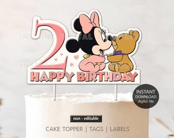 May include: Pink and white cake topper featuring a cartoon Minnie Mouse holding a teddy bear. The topper says "Happy Birthday" and has a pink number 2.