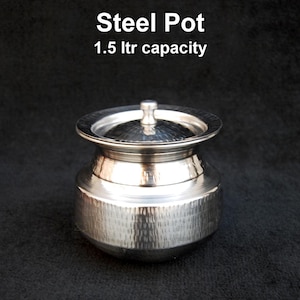 Puede incluir: Una olla de acero brillante con tapa, con una textura martillada en el cuerpo. El texto "Steel Pot" y "1.5 ltr capacity" se muestran encima de la olla. La olla tiene forma redondeada y un pequeño asa en la tapa.