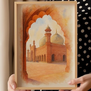 May include: A framed watercolour print depicting a mosque with a large dome and minarets. The artwork uses warm tones of orange, brown, and yellow, with a light blue sky. The mosque is framed by an archway, creating depth and perspective.