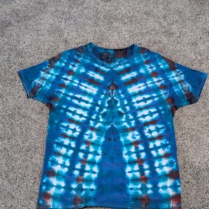 Tamanho G. Camisa tie-dye azul, vermelha e turquesa com estampa plissada.