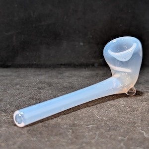 Peut inclure: Une pipe en verre blanc avec un bol incurvé et un long manche fin.