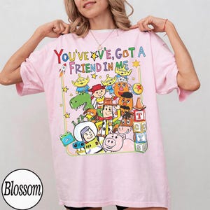 May include: A white ceramic mug with a black handle and the text "But First, Coffee" in a black, bold font. The mug is on a white surface. The mug is approximately 10 cm tall.