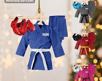 May include: A blue martial arts uniform with a white belt, red headgear, and gloves. The uniform has the word "NAME" on the chest. Additional uniforms in gray, red, and pink are also shown, each with different colored belts and headgear.
