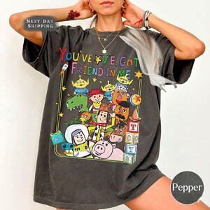 May include: A white ceramic mug with a black handle and the text "But First, Coffee" in a black, handwritten-style font. The mug is on a white surface.