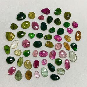 May include: Assortment of green, pink, and brown gemstones. The gemstones are faceted and have a variety of shapes and sizes.