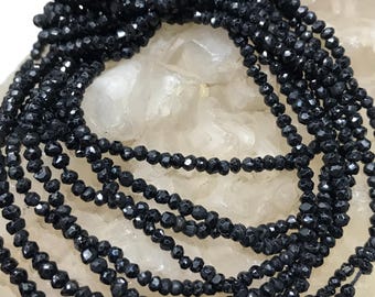 May include: A strand of black faceted gemstone beads. The beads are small and round, and they have a shiny, polished finish.