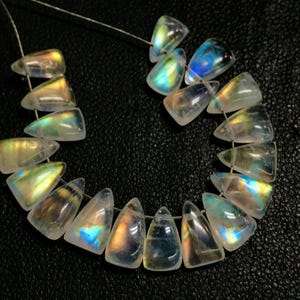May include: A strand of iridescent gemstone beads, each bead is a triangular shape with a pointed tip. The beads are strung on a silver wire and have a rainbow sheen.