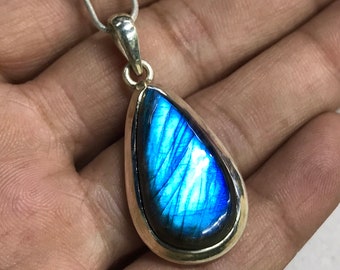 Pode incluir: Um colar de prata com um pingente de pedra de labradorita azul em forma de lágrima.