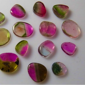 May include: A collection of 14 smooth, polished, multi-colored gemstones. The stones are various shades of pink, green, and yellow. They are all different shapes and sizes.