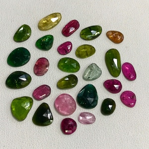 May include: Assortment of green, pink, and red gemstones, some with a pear shape, others with a rounded shape.