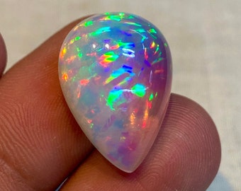 May include: A teardrop-shaped opal gemstone with a white base and iridescent rainbow colors, including green, blue, red, and pink.