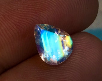 May include: A pear-shaped iridescent gemstone with a rainbow of colors, including blue, green, yellow, and orange.