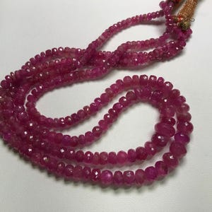May include: A strand of pink ruby beads, faceted and strung on a cord. The beads are small and uniform in size, creating a delicate and elegant look.