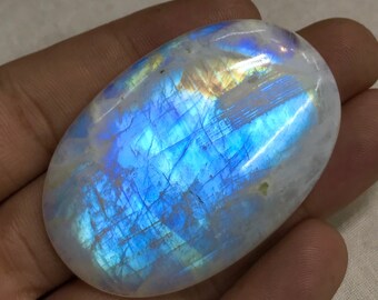 Könnte beinhalten: Ein großer, ovaler Mondstein mit einem blauen und irisierenden Schimmer. Der Stein ist glatt und poliert, mit einer weißen Grundfarbe.