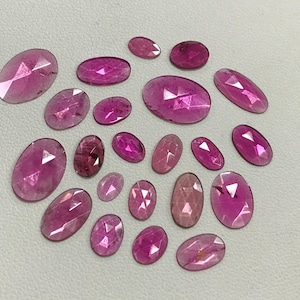 May include: A collection of 20 oval-shaped pink gemstones. The gemstones are faceted and have a translucent appearance.