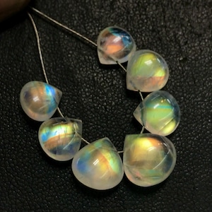 May include: A strand of iridescent rainbow moonstone teardrop beads. The beads are strung on a silver thread and have a pearlescent finish.