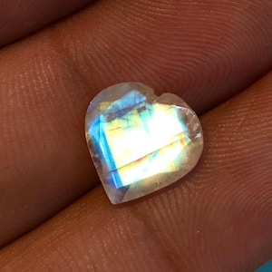May include: A heart-shaped iridescent gemstone displaying a rainbow of colours, including blue, green, yellow, and orange.