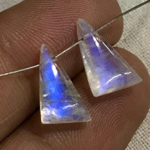 May include: Two iridescent rainbow moonstone triangle shaped beads with a silver wire threaded through them.