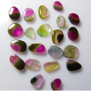 May include: A collection of 20 colorful, natural, and smooth, polished gemstones. The stones are a mix of green, pink, and black with some having a shimmery, iridescent effect.