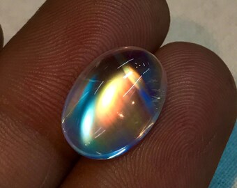 May include: Oval-shaped iridescent gemstone with a rainbow of colors, including blue, green, orange, and yellow.