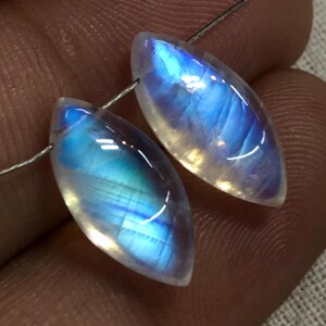 May include: Two iridescent blue and white moonstone cabochons, each with a marquise shape, are strung on a silver wire.