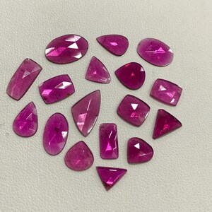 May include: A collection of 18 pink gemstones of various shapes and sizes. The gemstones are faceted and have a translucent appearance.