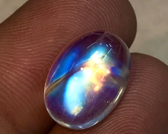 May include: A clear oval-shaped gemstone with iridescent rainbow colors, showing blue, purple, and orange hues.