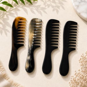May include: Four wide-tooth hair combs arranged in a row. The first comb on the left is brown and black with a marbled pattern. The second comb features a cream and black marbled design. The third and fourth combs are solid black in color.