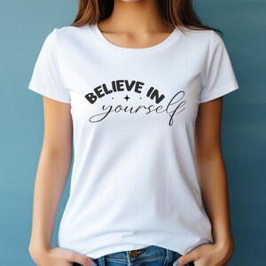 May include: White t-shirt featuring the words "BELIEVE IN yourself" in black script, with a star graphic. The top has short sleeves and a crew neck.