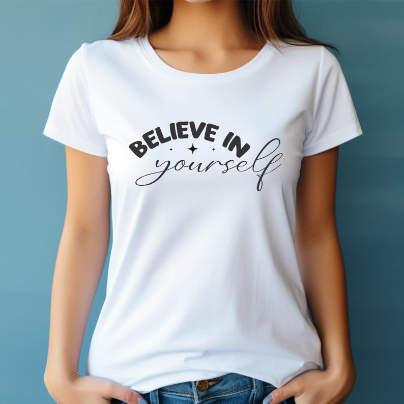 May include: White t-shirt featuring the words "BELIEVE IN yourself" in black script, with a star graphic. The top has short sleeves and a crew neck.