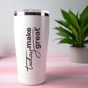 May include: A white insulated travel mug with a silver rim and lid. The mug has the words "Today. make great" in black script. A green plant in a white pot is in the background.