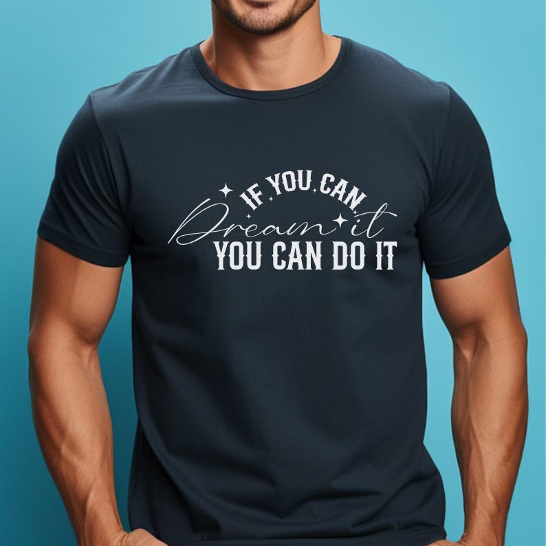 May include: Dark navy blue t-shirt featuring the white text "If you can dream it, you can do it." The text is in a decorative font with star accents. The t-shirt has a crew neck.