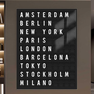 Könnte beinhalten: Ein schwarzes Wandpaneel mit weißen Texten von internationalen Städtenamen: Amsterdam, Berlin, New York, Paris, London, Barcelona, Tokio, Stockholm und Mailand. Das Schild ist rechteckig und hat ein Raster aus einzelnen Buchstabenfächern.