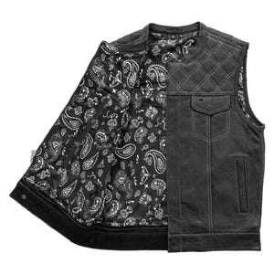 Puede incluir: Chaleco de cuero negro con diseño acolchado en los hombros y dos bolsillos delanteros. El interior del chaleco presenta un estampado de cachemir en blanco y negro. El chaleco está abierto, revelando el forro estampado.