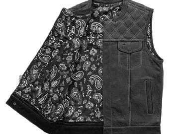 Könnte beinhalten: Schwarze Lederweste mit einem gesteppten Schulterdesign und zwei Vordertaschen. Das Innere der Weste weist ein schwarz-weißes Paisley-Muster auf. Die Weste ist offen und zeigt das gemusterte Futter.
